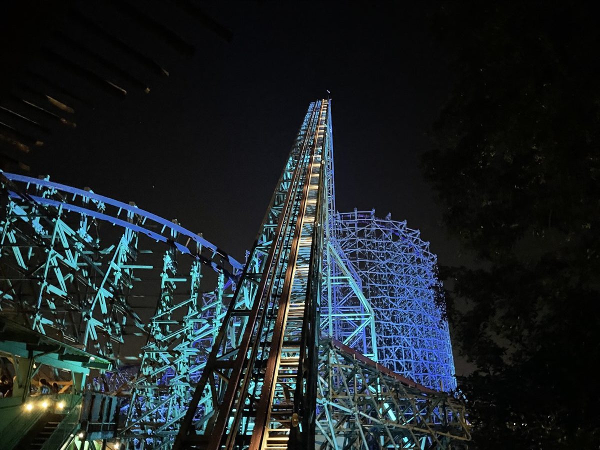 Wood-steel hybrid roller coaster track illuminated at night