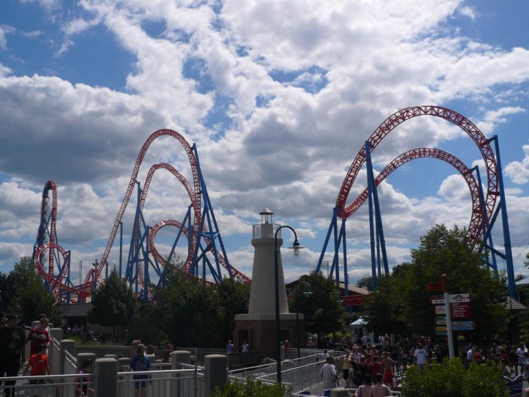 Steel roller coaster climbing a near-vertical lift hill against a blue sky